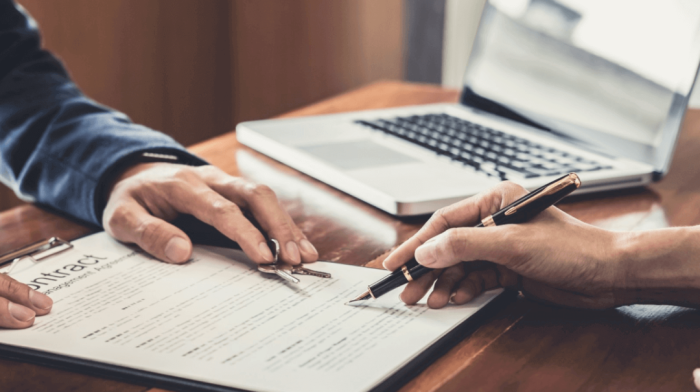 close up of hands signing a contract