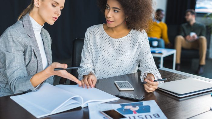 multicultural businesswomen talking about documents in office